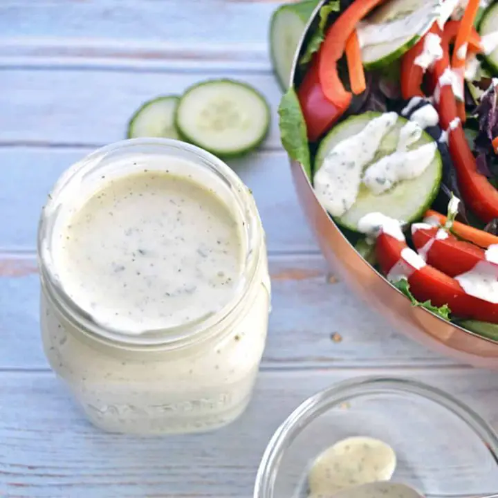 overhead shot of low fodmap ranch dressing in a jar next to a salad covered in ranch dressing