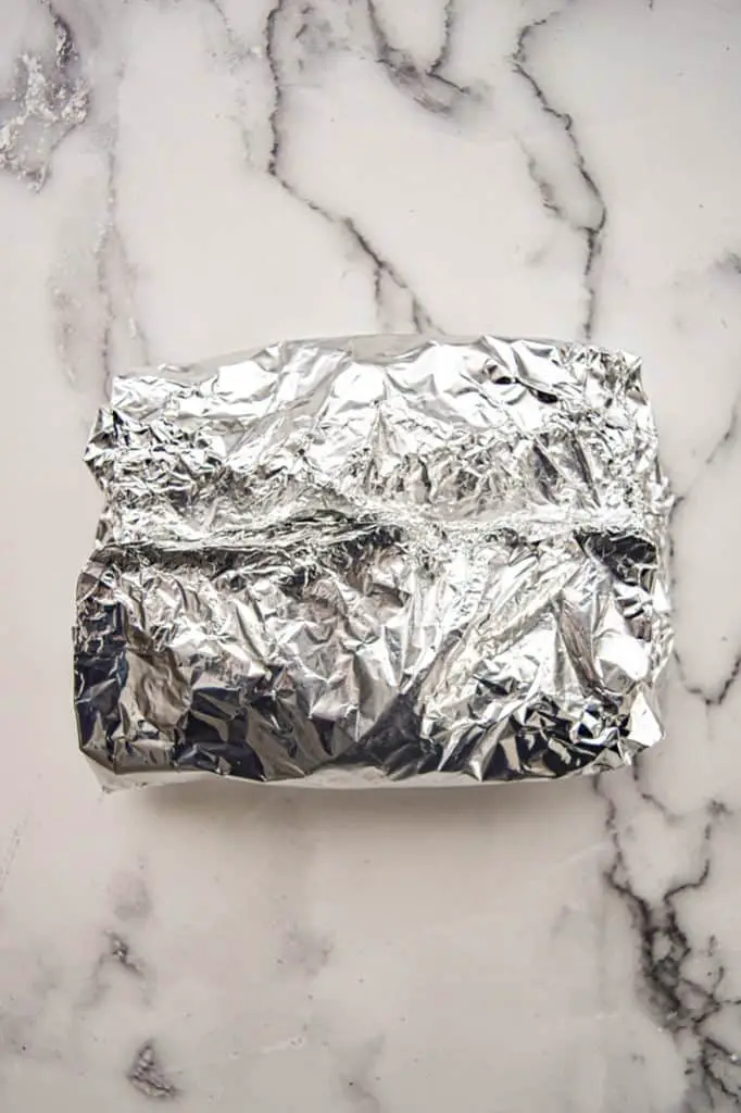 sealed foil packet holding the frozen green beans on a white marble background