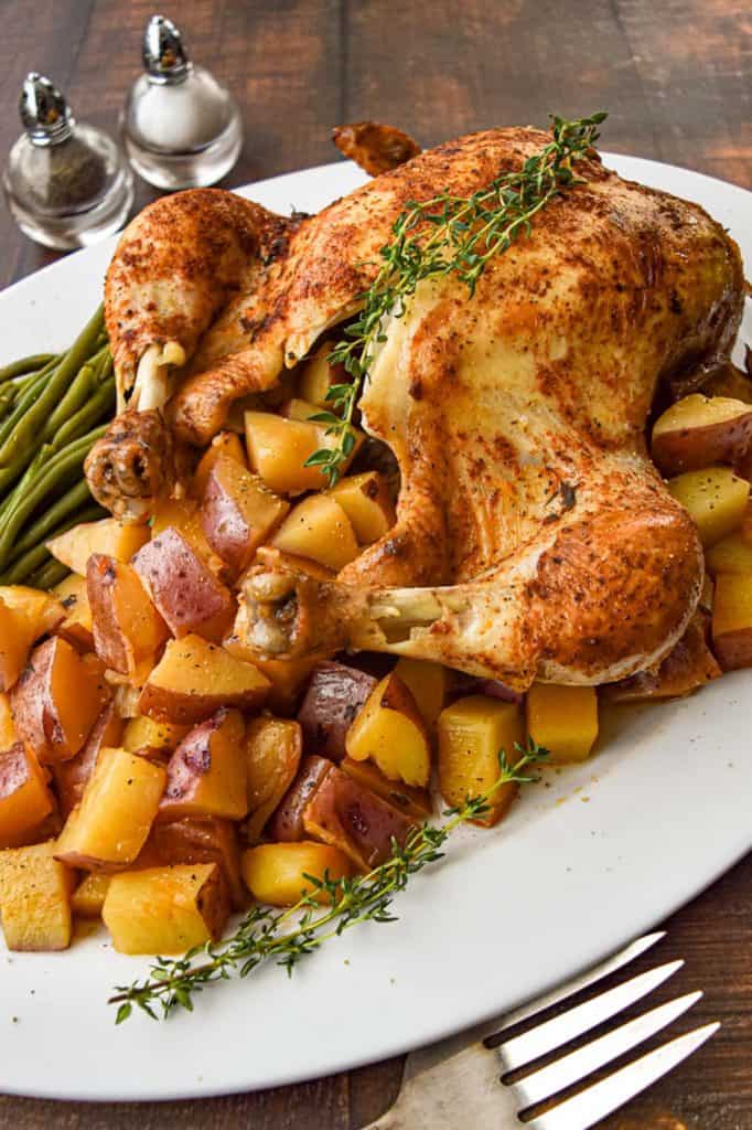 low fodmap whole chicken on a white platter with red potatoes and green beans