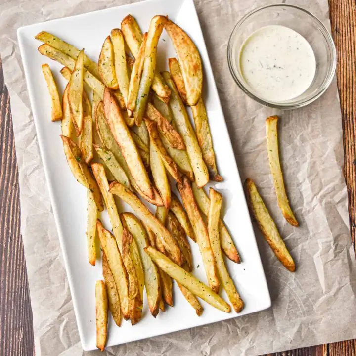 overhead shot of low fodmap air fryer french fries on a rectangular plate next to a bowl of ranch dressing