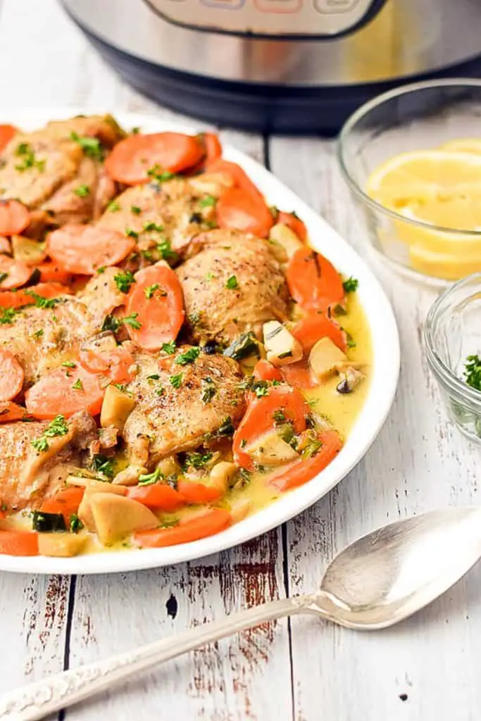 low fodmap chicken fricassee on a platter next to a spoon, bowls of lemons and parsley and an instant pot