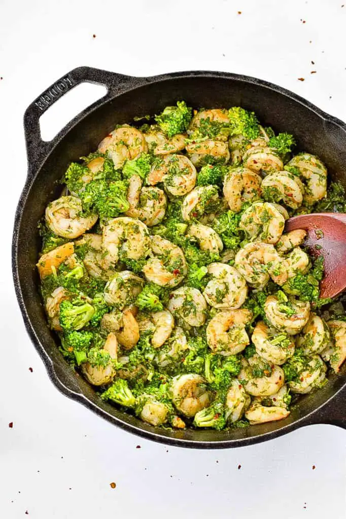 low fodmap chimichurri shrimp and broccoli skillet in a cast iron pan on a white background