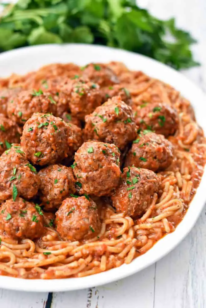 low fodmap instant pot spaghetti and meatballs on a platter in front of a bunch of parsley
