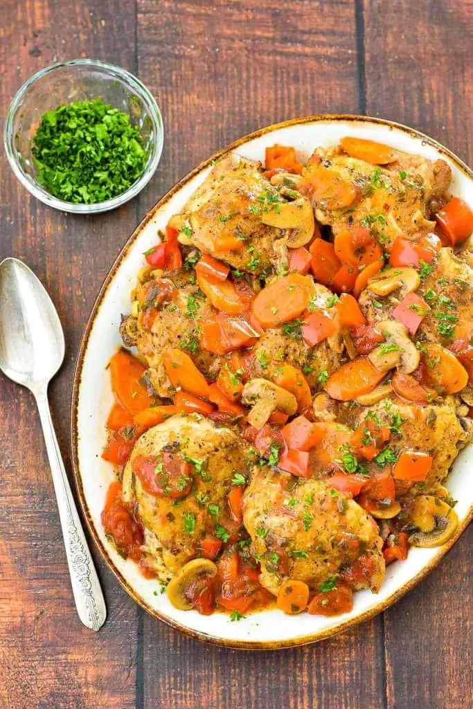 low fodmap instant pot chicken cacciatore on a brown rimmed platter next to a spoon and bowl of parsley