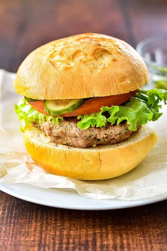 close up of a low fodmap turkey burger with pickle, tomato, and lettuce on a gluten-free bun