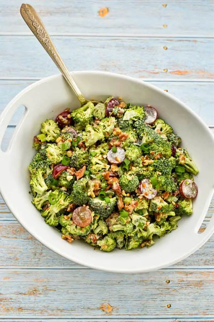 overhead shot of low fodmap broccoli salad with bacon in a white bowl with a spoon