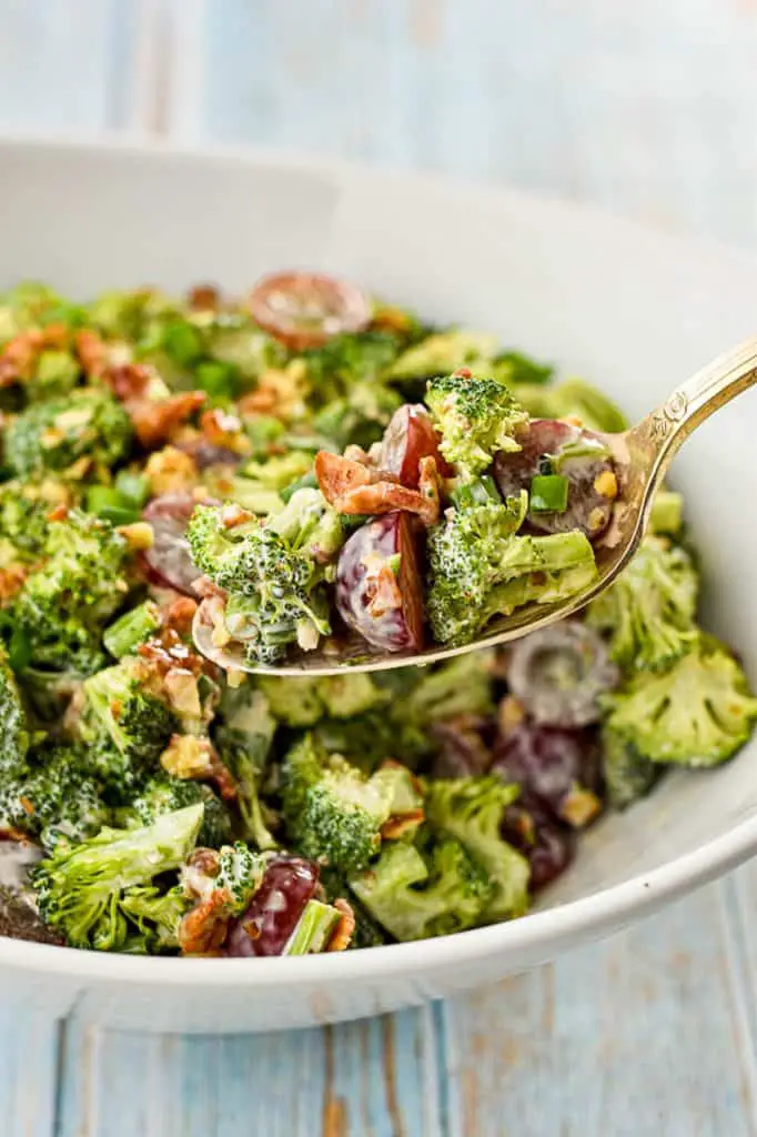 a spoonful of low fodmap broccoli salad with bacon over a bowl of salad