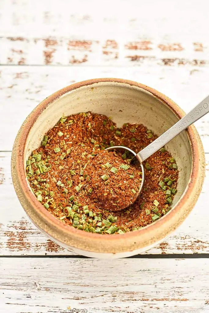 low fodmap taco seasoning in a pottery bowl with a measuring spoon on a white background