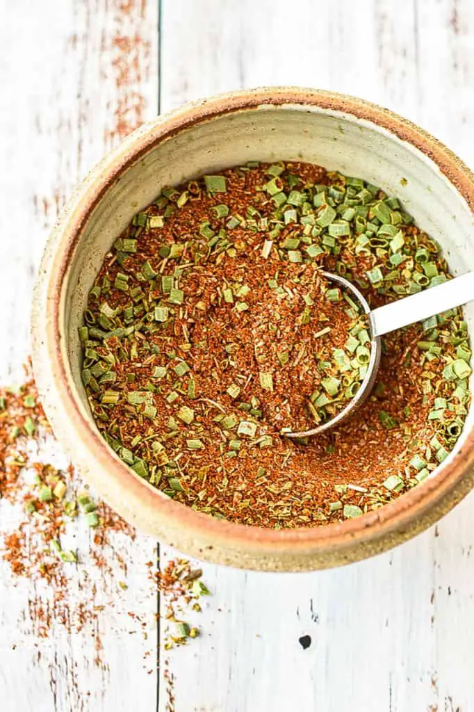 a bowl of low fodmap taco seasoning mix in a pottery bowl with a tablespoon inside