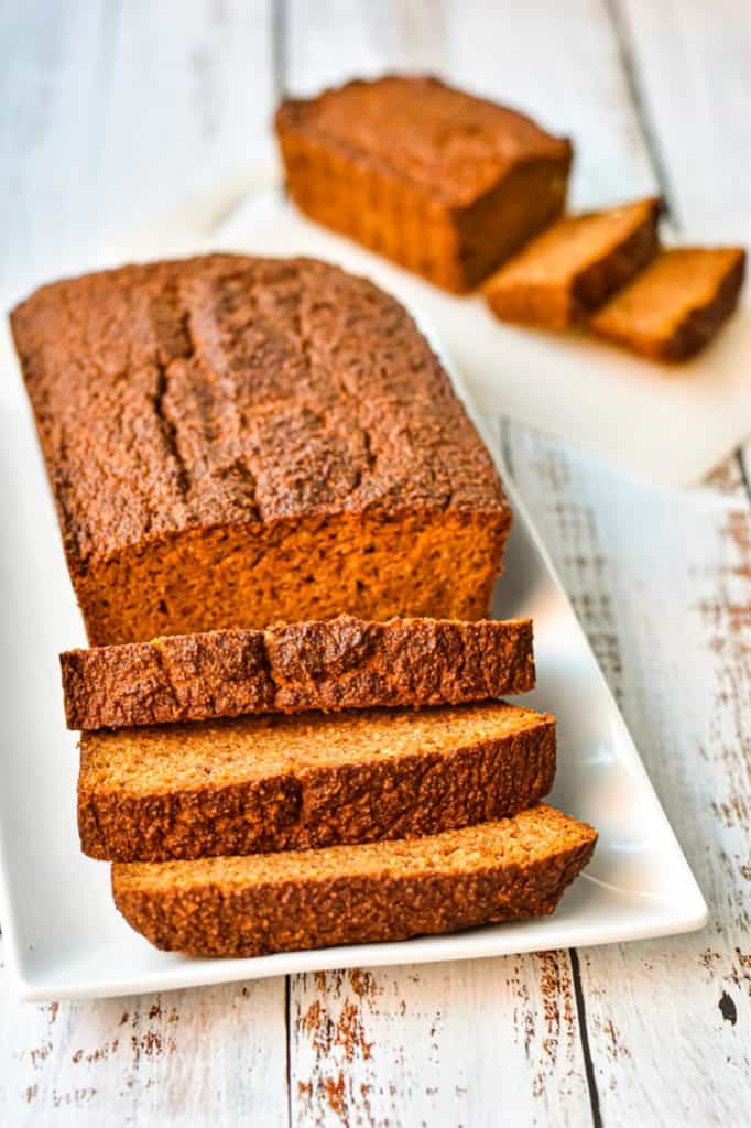 a large loaf of partially sliced low fodmap pumpkin bread in front of a mini loaf of partially sliced pumpkin bread