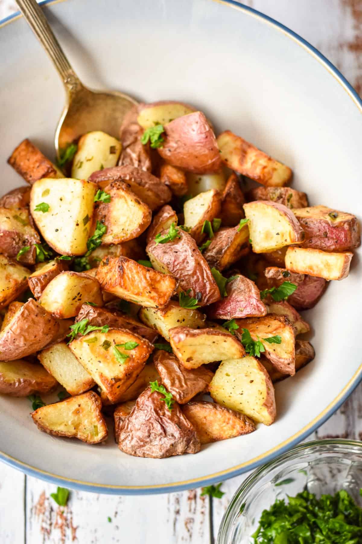 a close up of low fodmap air fryer red potatoes in a bowl with a spoon