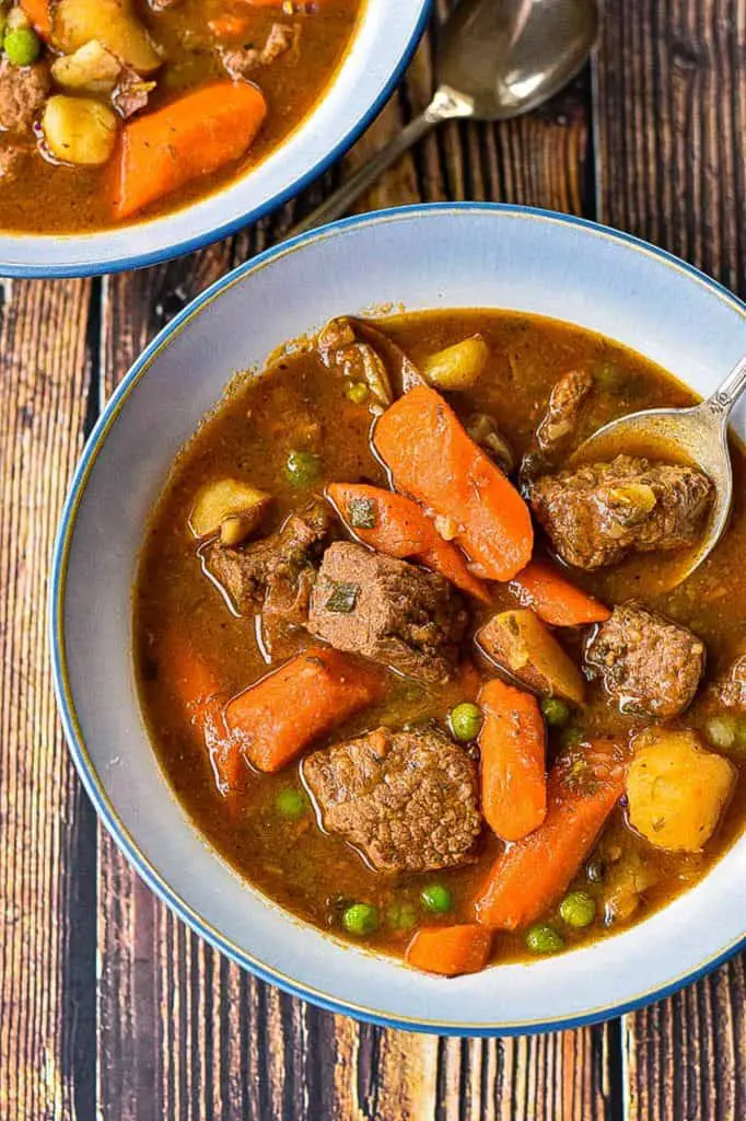 a bowl of low fodmap beef stew with a spoon and another bowl of stew and spoon behind