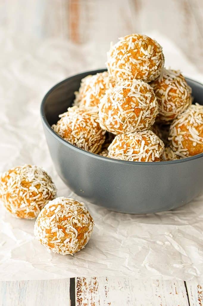 a navy blue bowl full of low fodmap carrot cake protein bites covered in shredded coconut