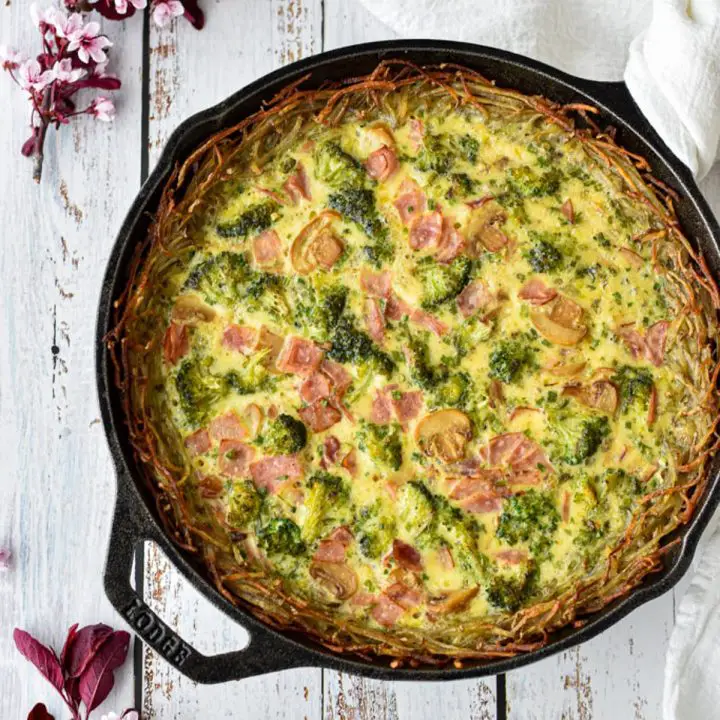 overhead shot of low fodmap quiche with a hashbrown crust in a cast iron skillet.