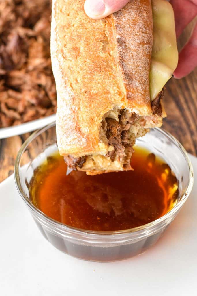 a bitten low fodmap french dip sandwich over a bowl of au jus