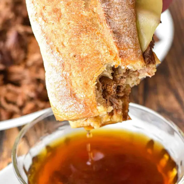 dipping a low fodmap french dip into a bowl of au jus