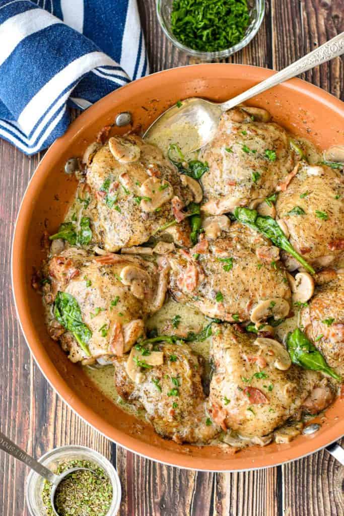 low fodmap chicken thighs covered in a creamy, bacon mushroom sauce in a copper skillet