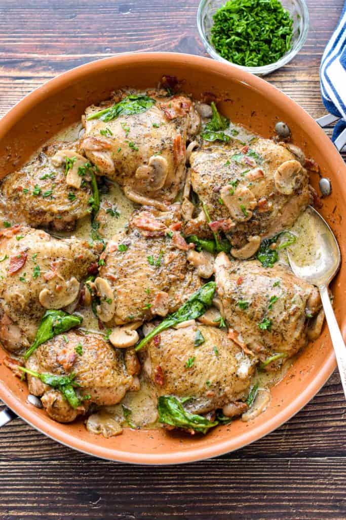 overhead low fodmap chicken thighs in a copper skillet with a spoon covered in sauce