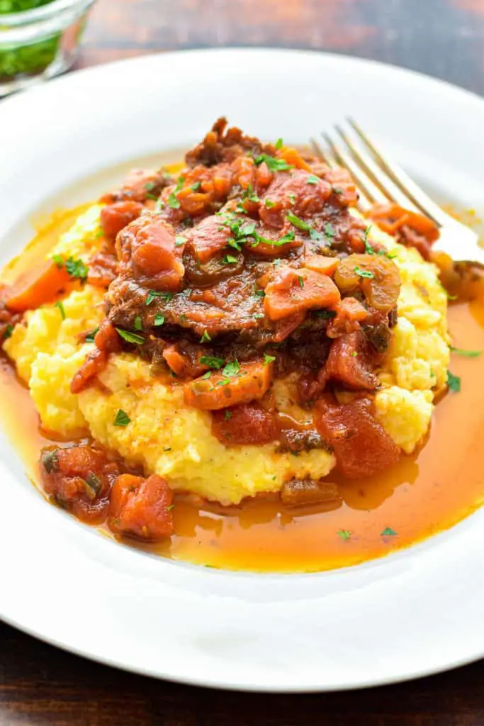 close up shot of low fodmap italian pot roast on polenta covered in tomato vegetable sauce