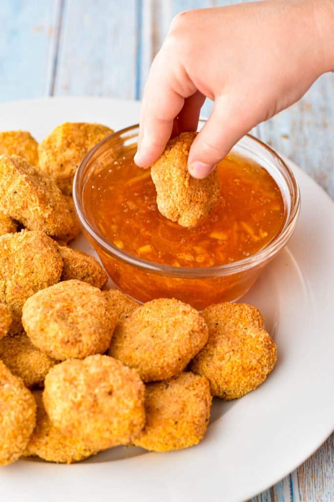 dipping an air fryer chicken nugget into a bowl of low fodmap sweet and sour dipping sauce