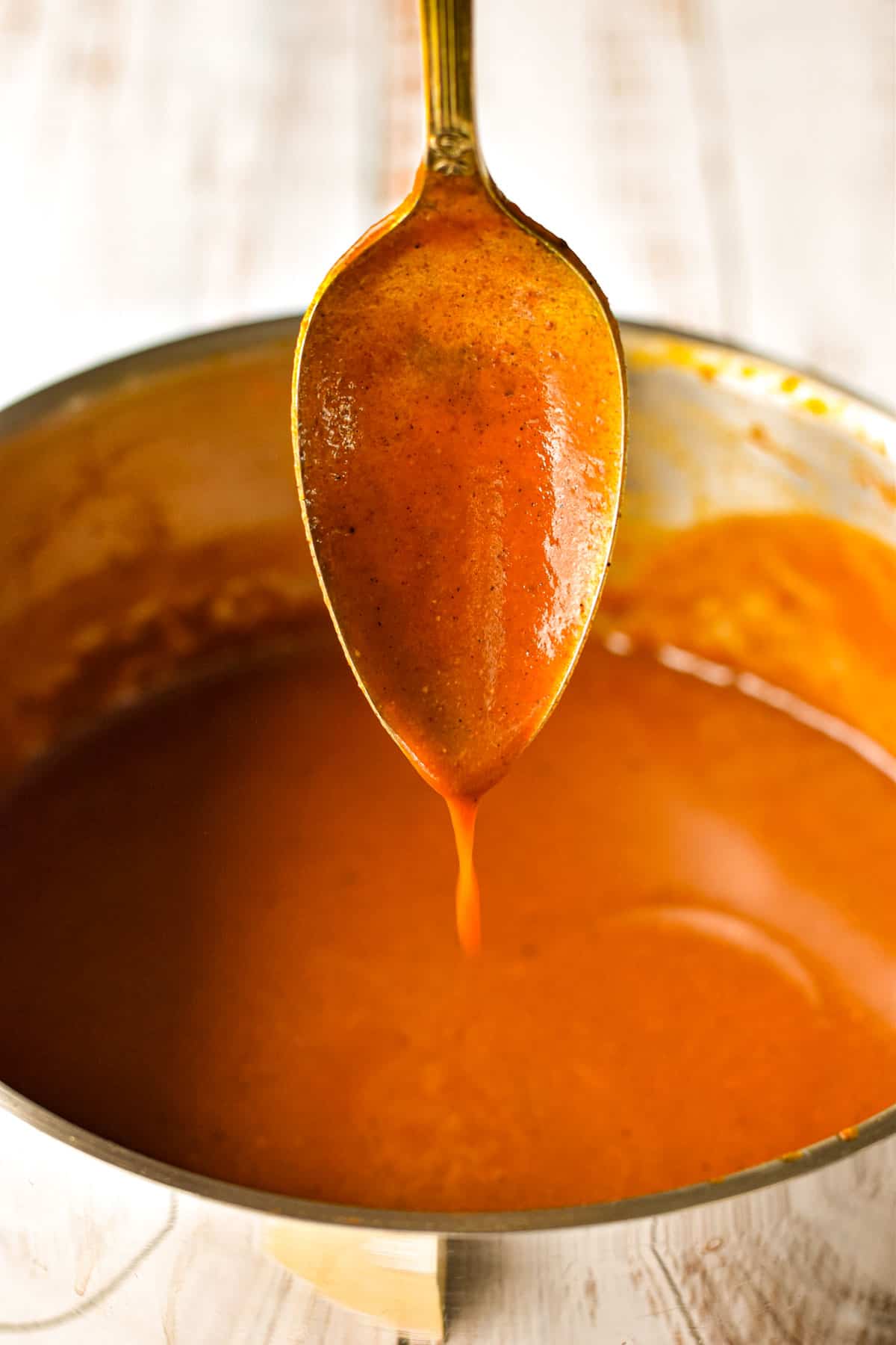 low fodmap enchilada sauce dripping from a spoon into a pot