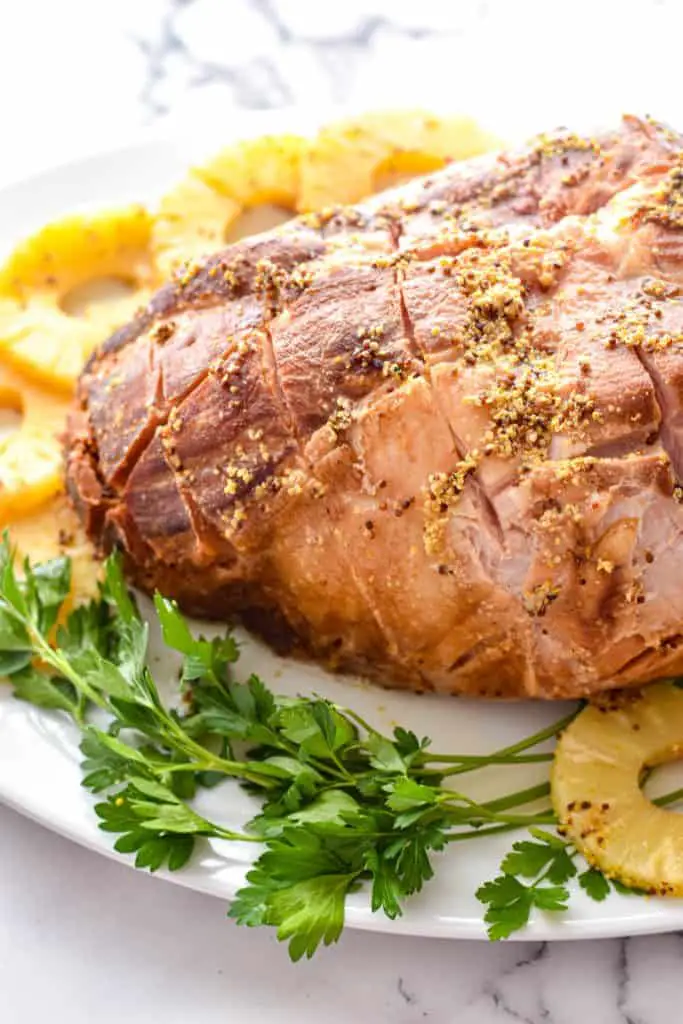 uncut low fodmap slow cooker ham on a platter with parsley and pineapple