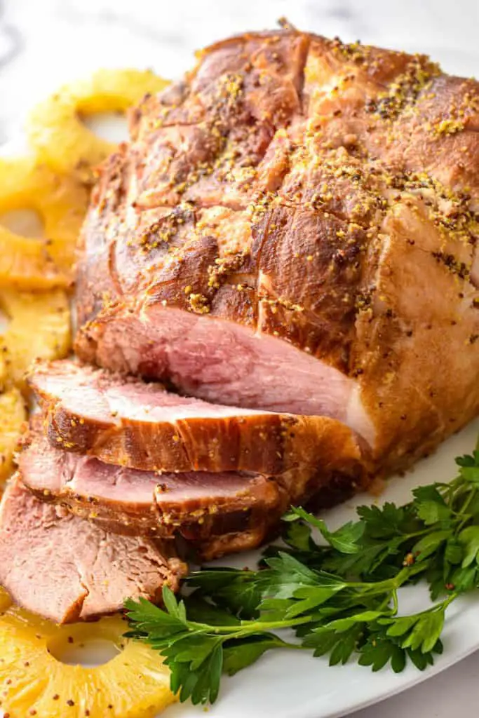 low fodmap slow cooker ham on a platter with pineapple rings and parsley sprigs