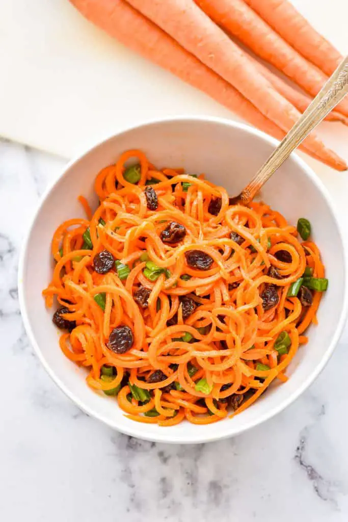 overhead shot of low fodmap carrot salad containing spiralized carrots, raisins and green onions