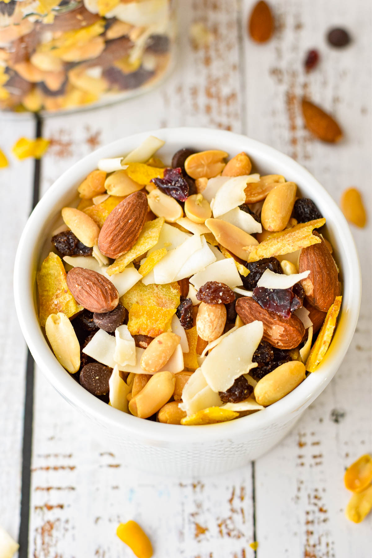 close up shot of low fodmap trail mix in a white bowl on a painted white wooden background