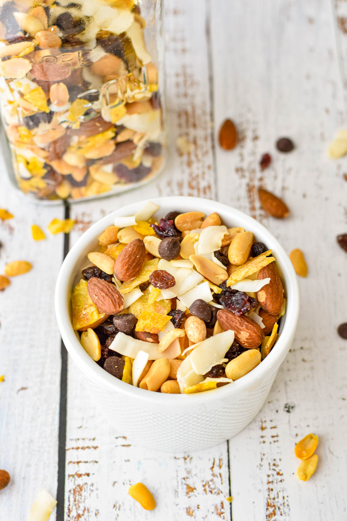 low fodmap trail mix in a white ramakin in front of a mason jar of trail mix on a white background