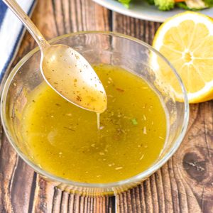 low fodmap italian salad dressing drizzling out of a spoon into a bowl of dressing