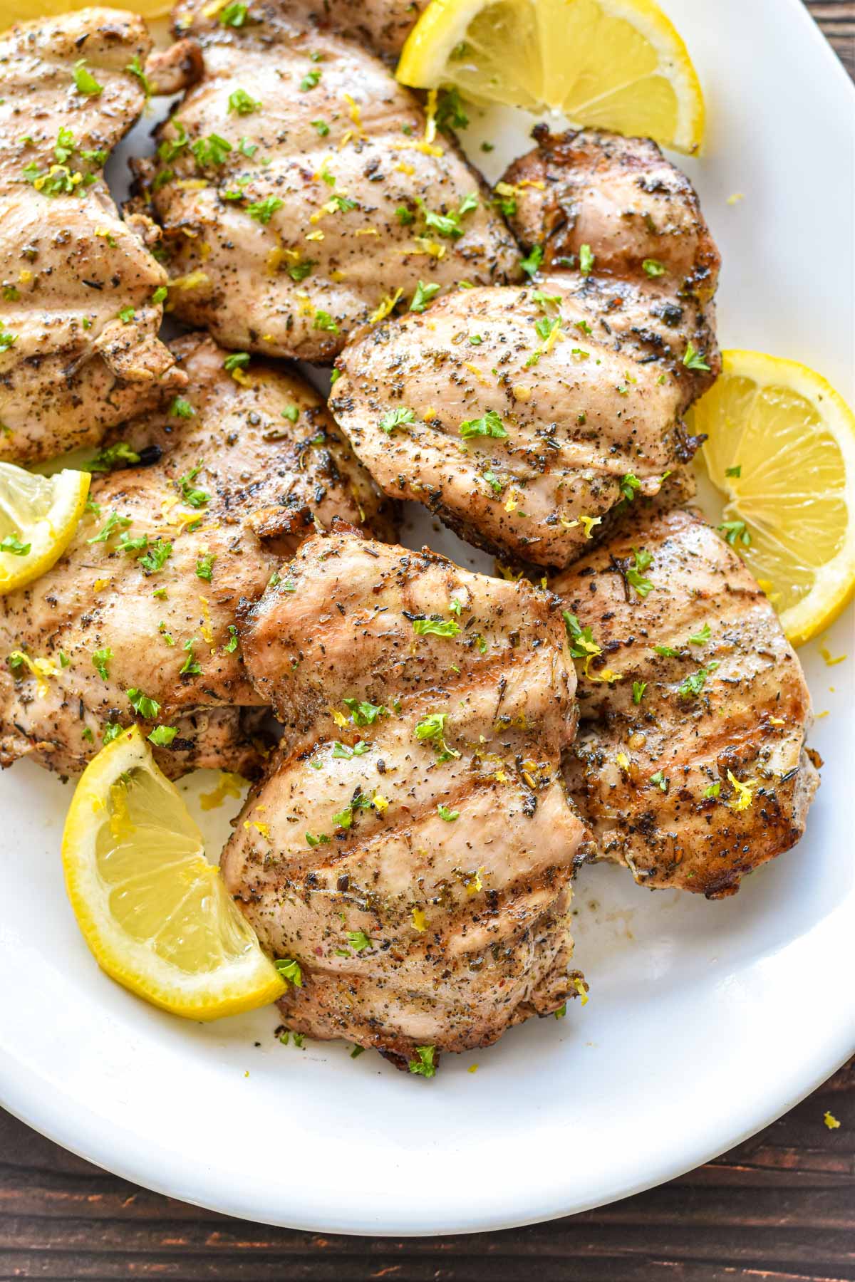 low fodmap marinated grilled chicken thighs on a white platter with lemon slices