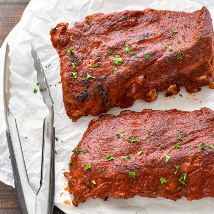 low fodmap ribs covered in bbq sauce on parchment paper with tongs