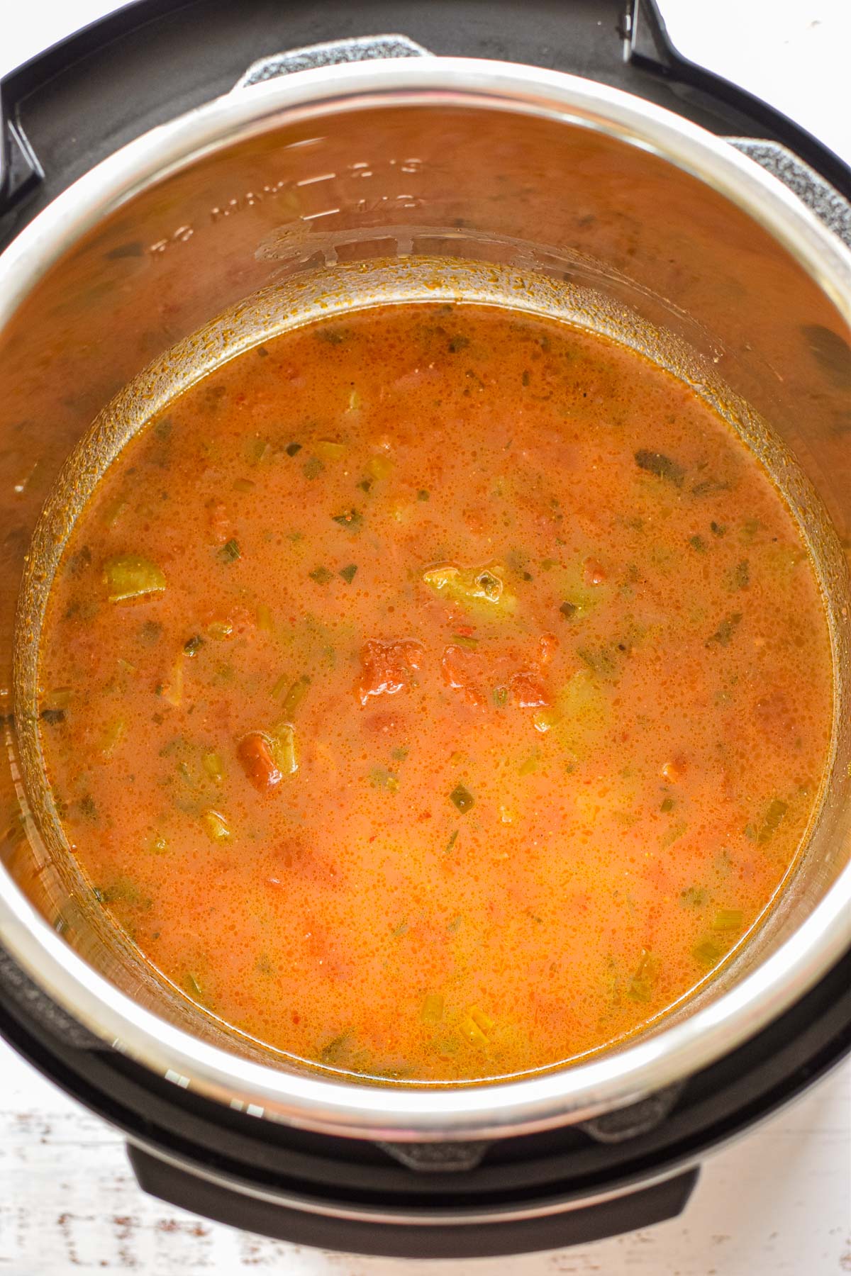 process shot of low fodmap salsa mixed with chicken bone broth in the bottom of an instant pot