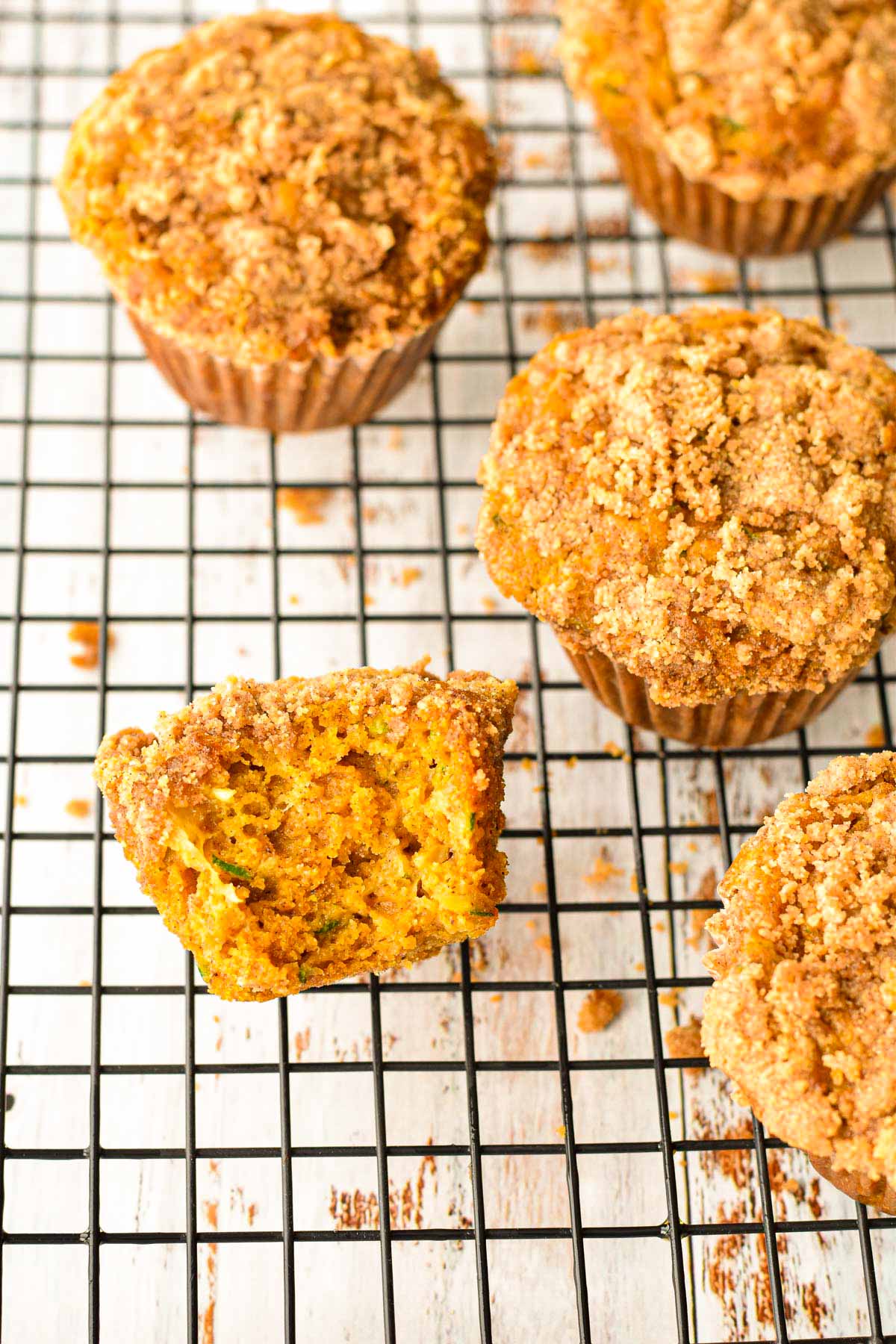 low fodmap pumpkin muffins with zucchini on a black wire rack a muffin with a bite taken out of it to show the inside