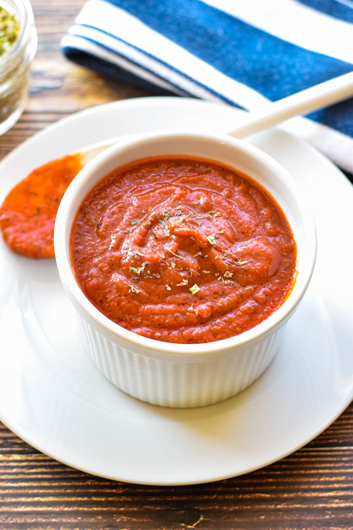 low fodmap pizza sauce in a small bowl on a plate with a sauce covered spoon