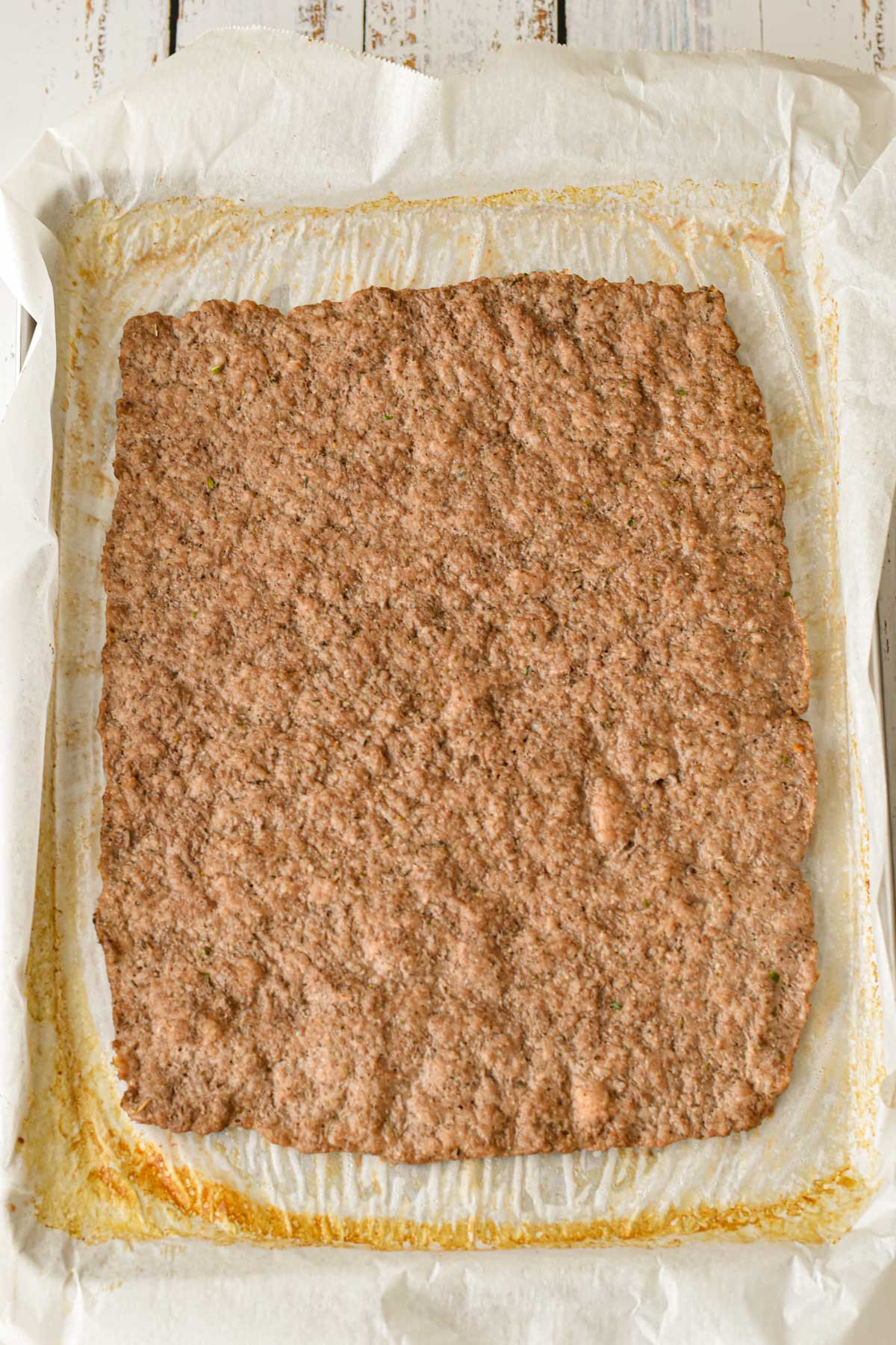 process shot of low fodmap meatza crust after it's baked and grease is drained but before toppings are added