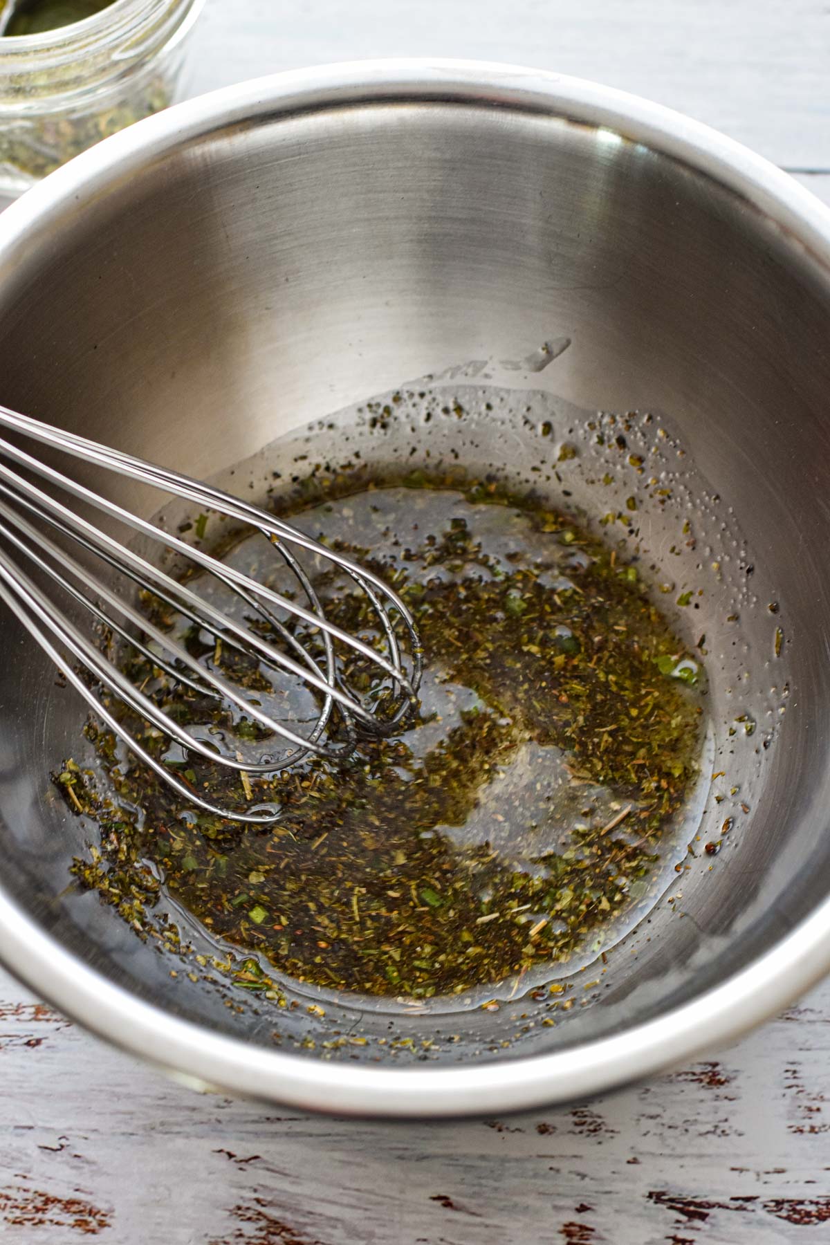 process shot of whisking together oil, low fodmap Italian seasoning, salt and pepper in a small mixing bowl