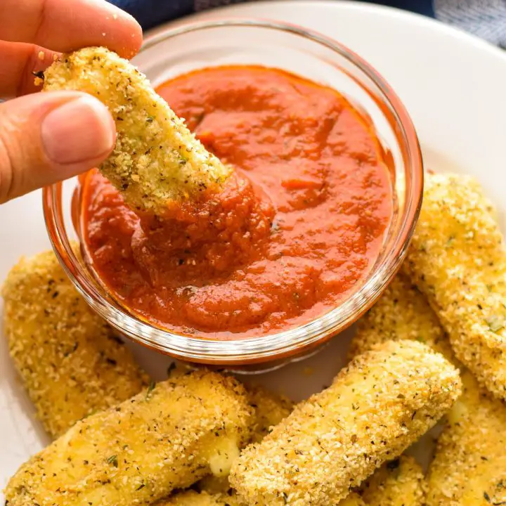 low fodmap mozzarella stick appetizer being dipped into low fodmap pizza sauce