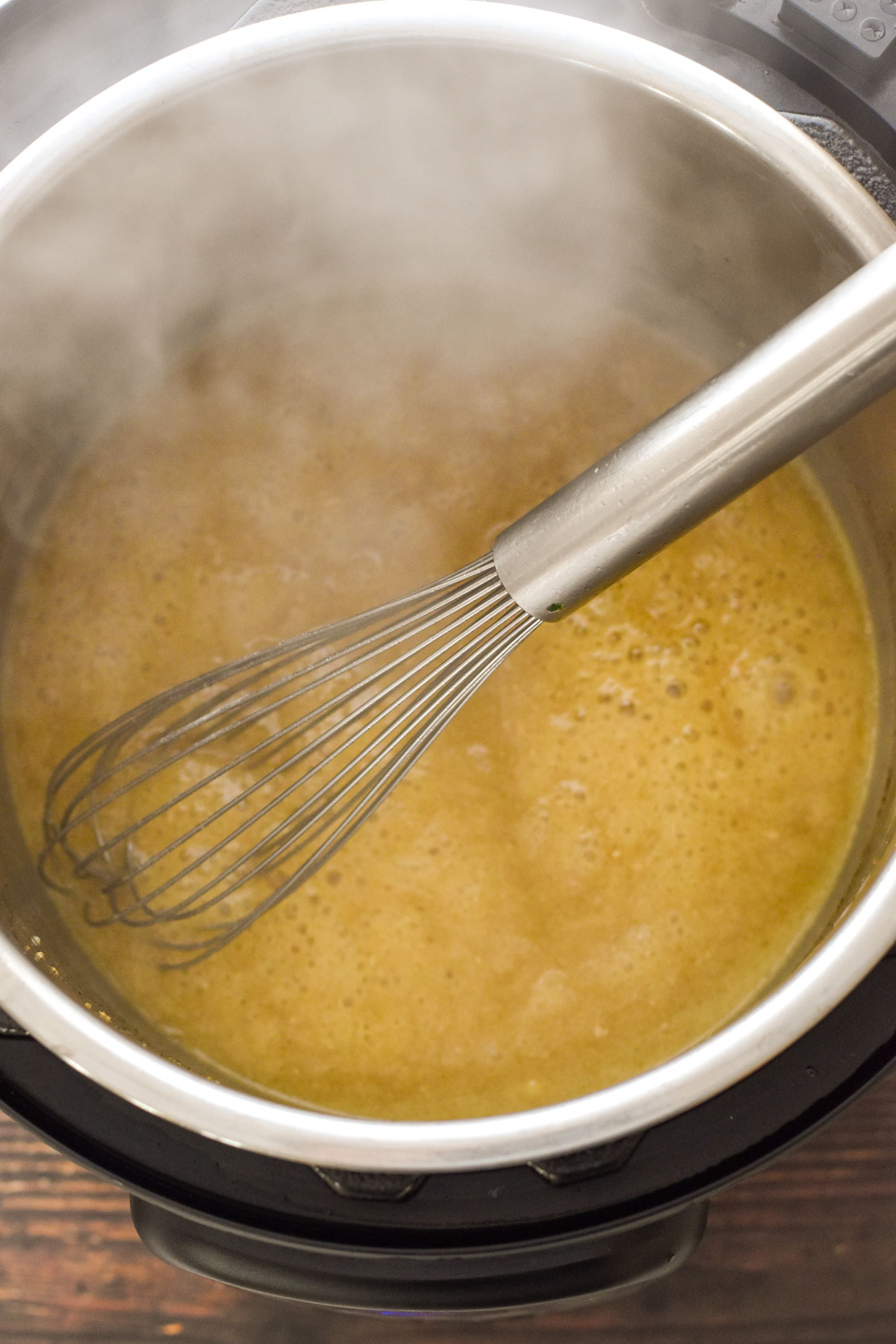 process shot of whisking gravy while it thickens in the instant pot after xanthan gum is added