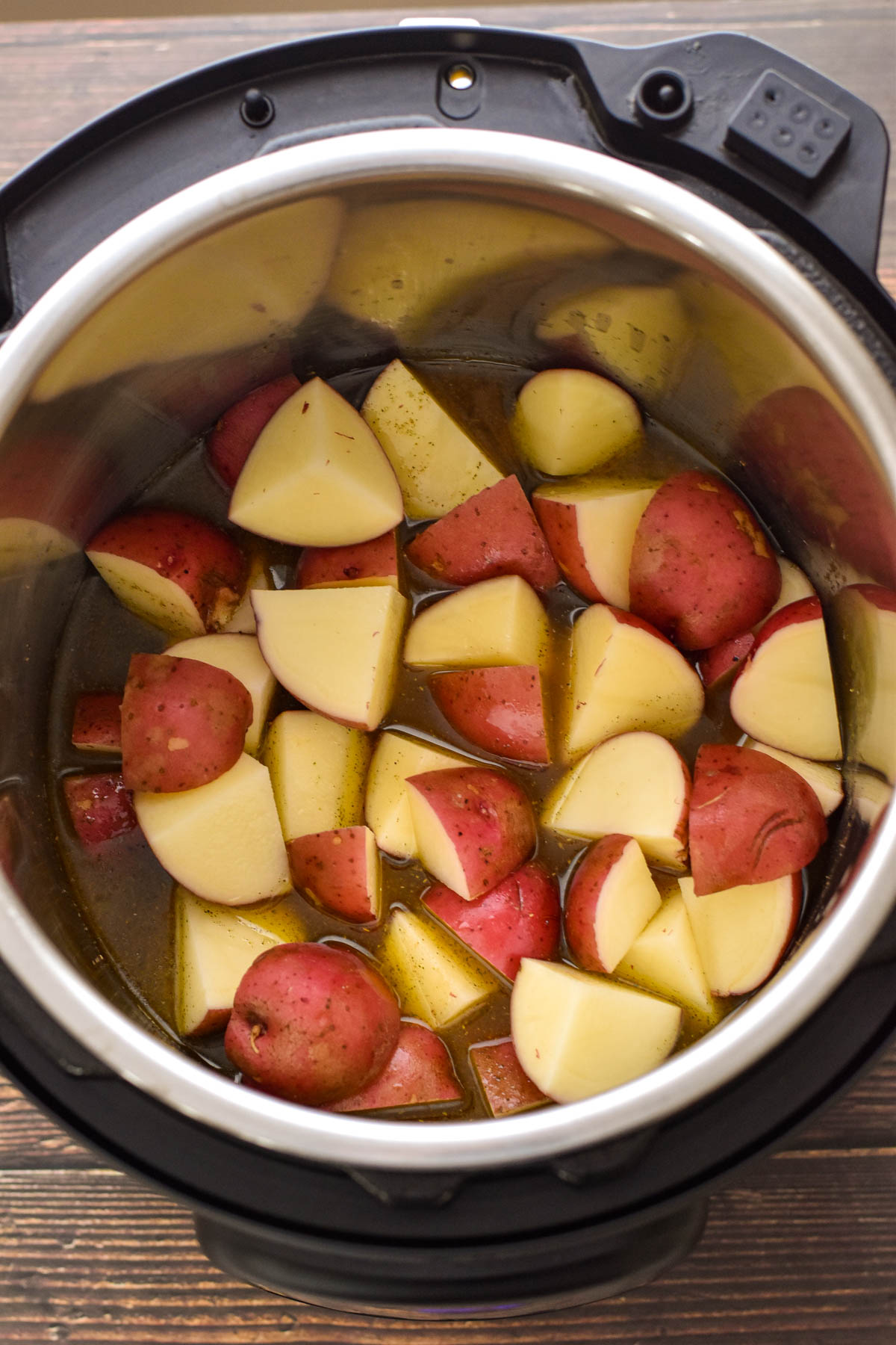 process shot of after chopped red potatoes have been added to the instant pot evenly in the gravy broth
