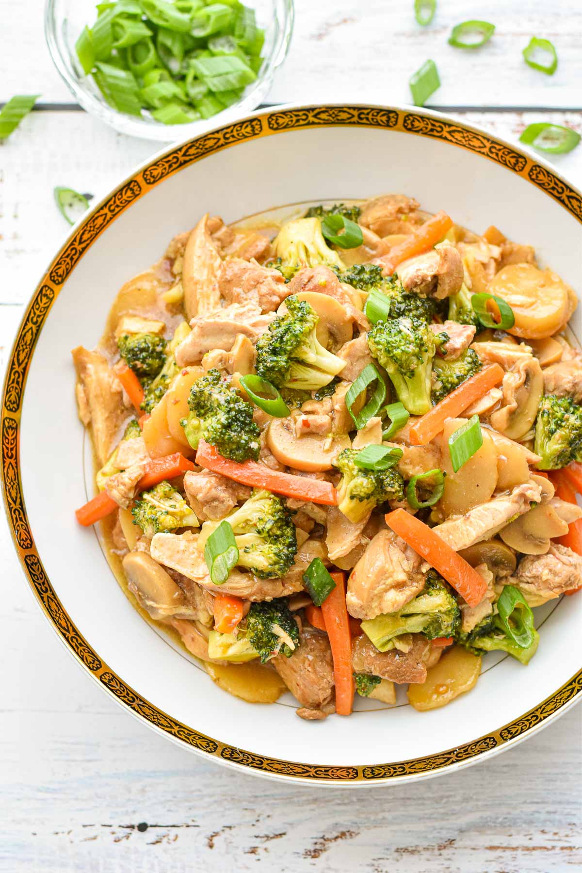 overhead shot of low fodmap instant pot chicken stir fry with vegetables in a white bowl with gold and black trim
