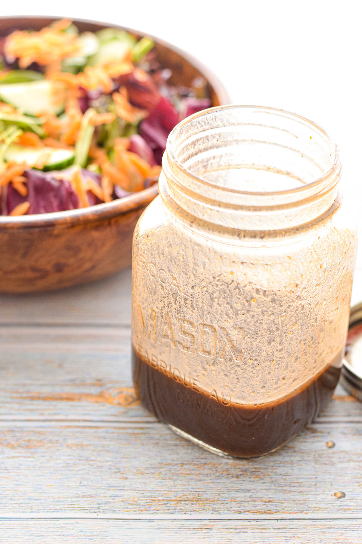 low fodmap low carb balsamic vinaigrette in a mason jar in front of a salad in a wooden bowl