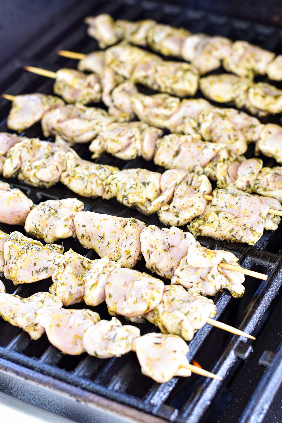 process shot of grilling low fodmap greek chicken souvlaki on a natural gas outdoor grill