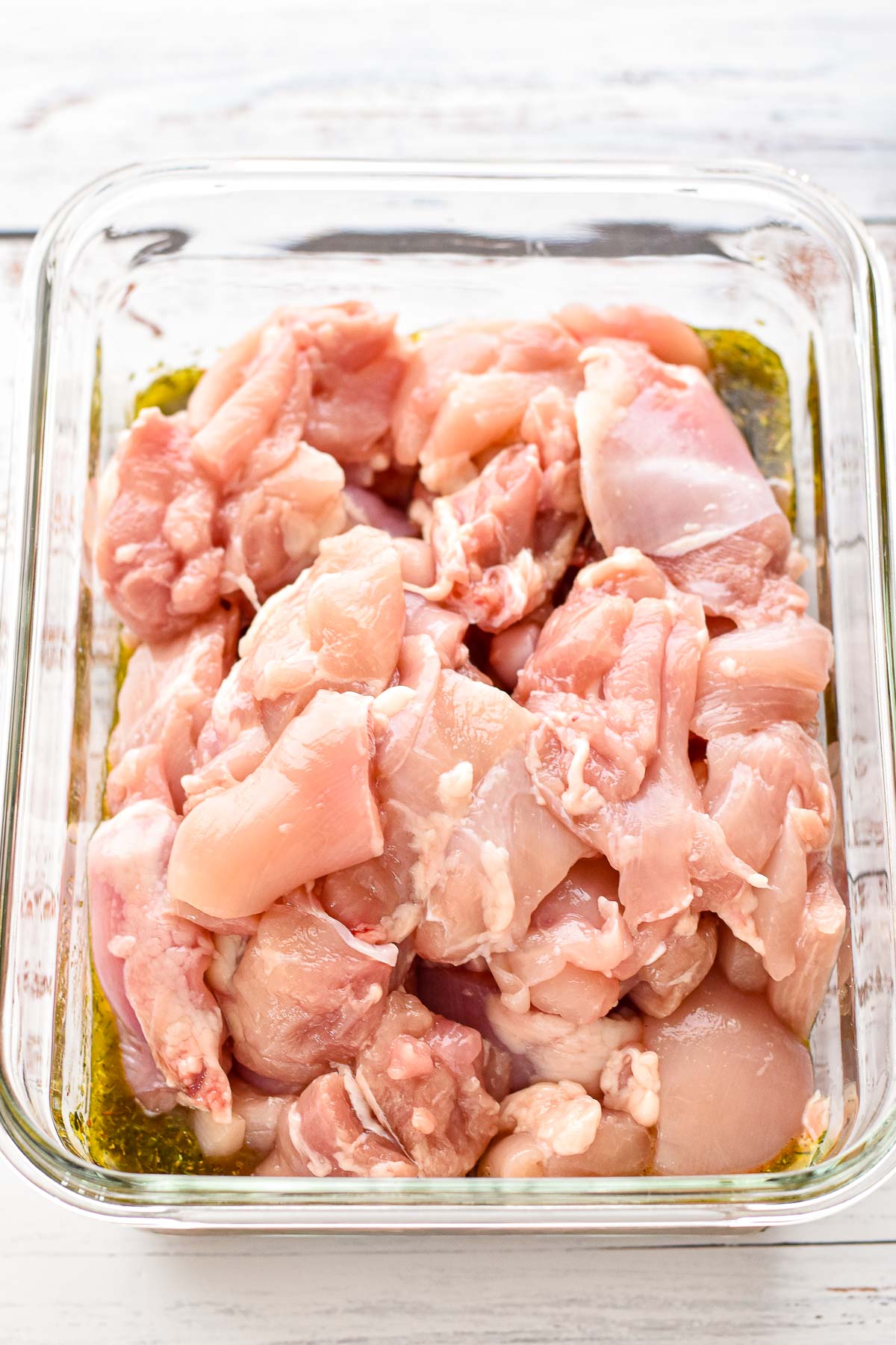 process shot after chicken thigh pieces are added to the container with greek souvlaki marinade