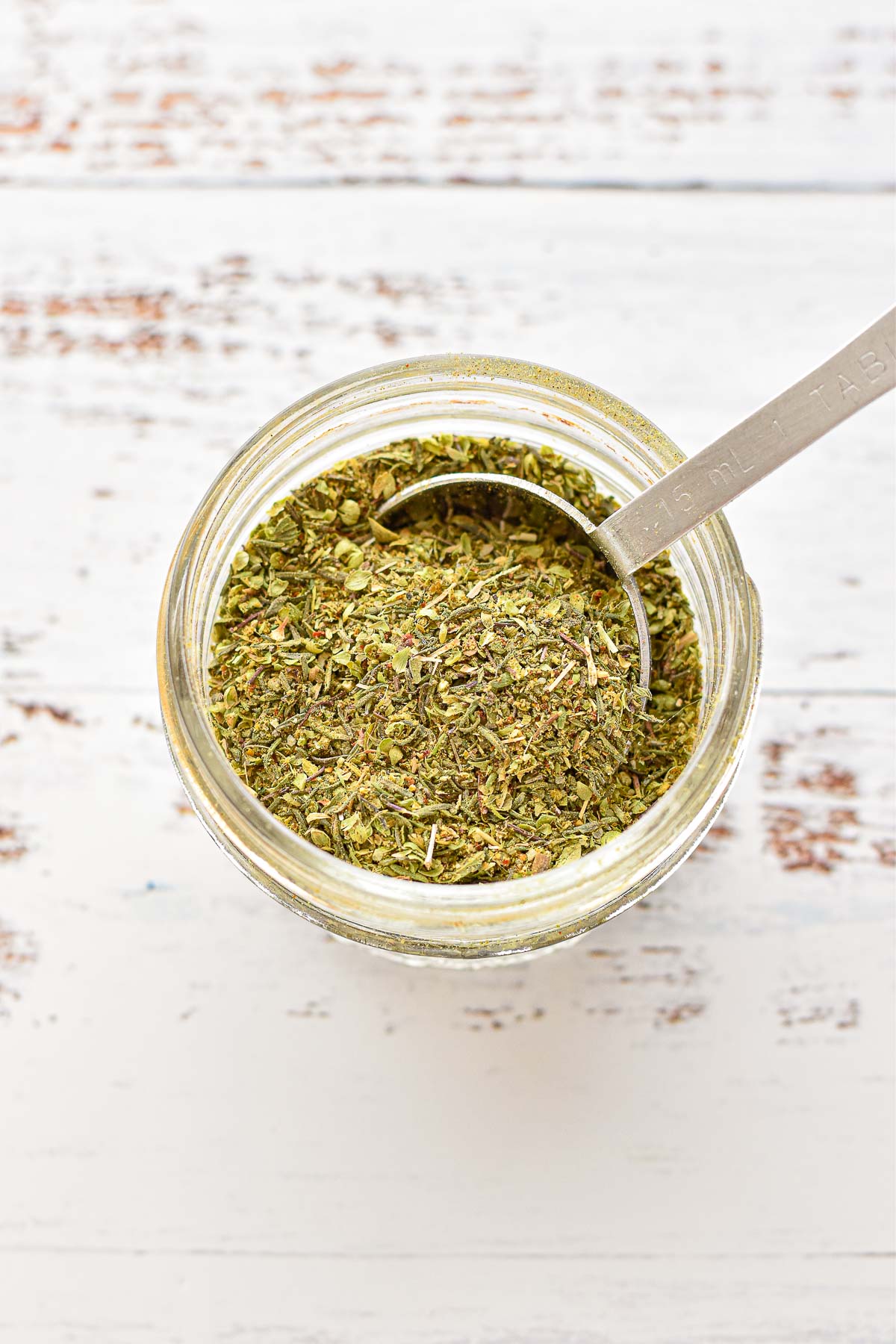 overhead shot of low fodmap seasoning mix in a glass jar with a tablespoon