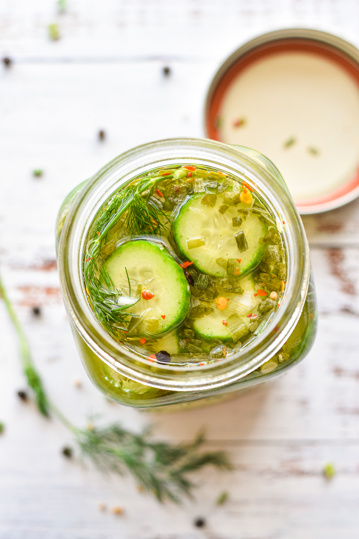 low fodmap pickles in a mason jar next to a sprig of fresh dill and spices