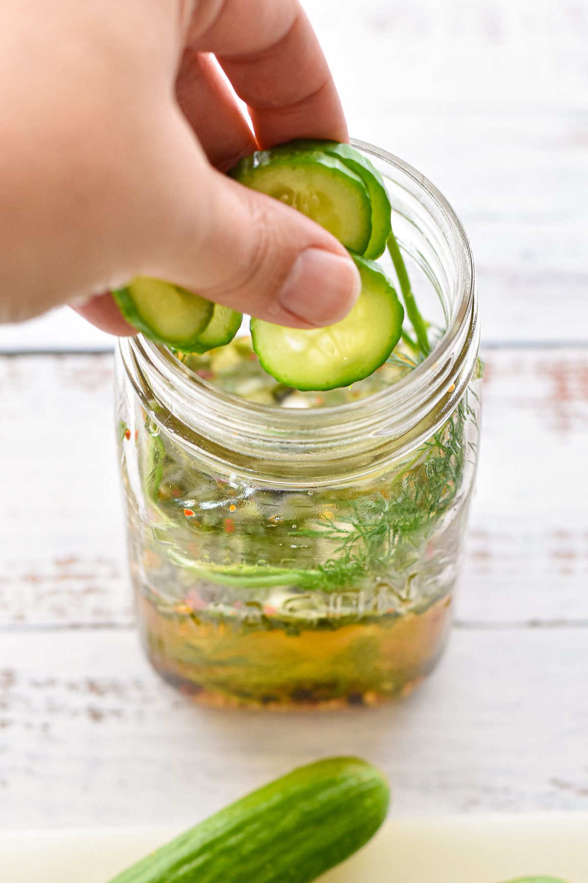process of adding cucumbers to jar containing pickle brine