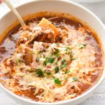 a spoon scooping low fodmap low carb lasagna soup in a white bowl.