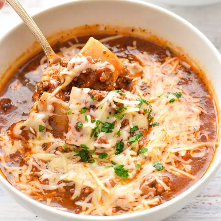 a spoon scooping low fodmap low carb lasagna soup in a white bowl.